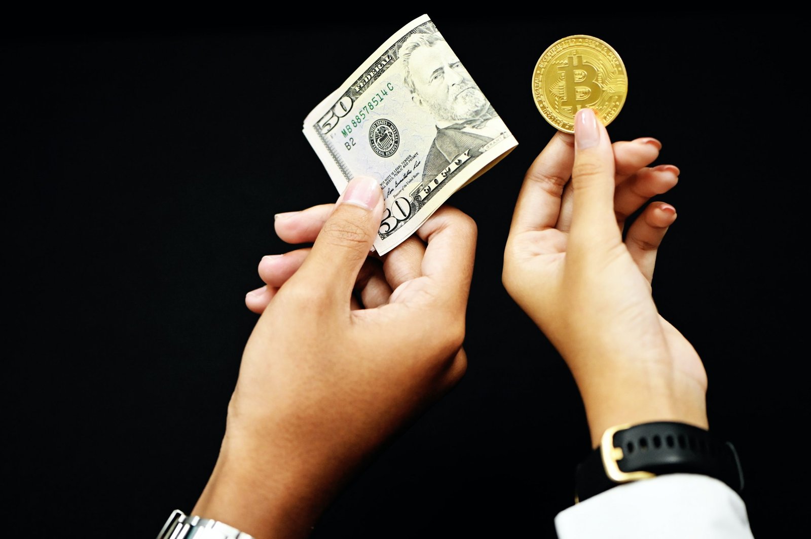 A hand holding a 50 dollar bill and a hand holdig a gold coin with the Bitcoin logo.